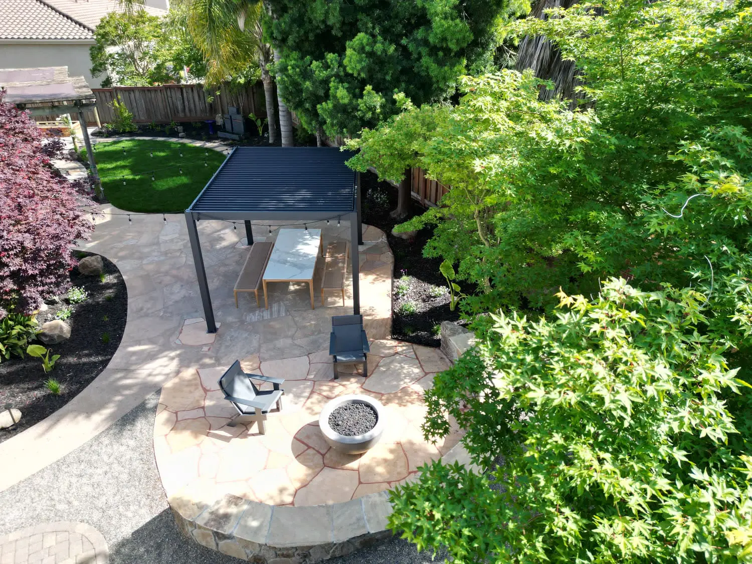 Aerial view of a custom flagstone patio, fire pit, and pergola structure designed by keystone-yards-calistoga-ca
