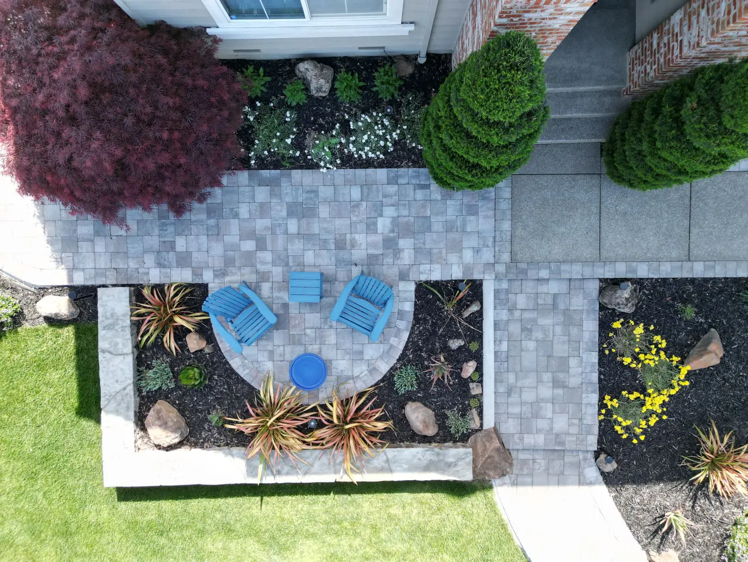 Overhead view of a modern backyard landscape with a stone patio, blue chairs, and custom garden beds designed by keystone-yards-san-rafael-ca