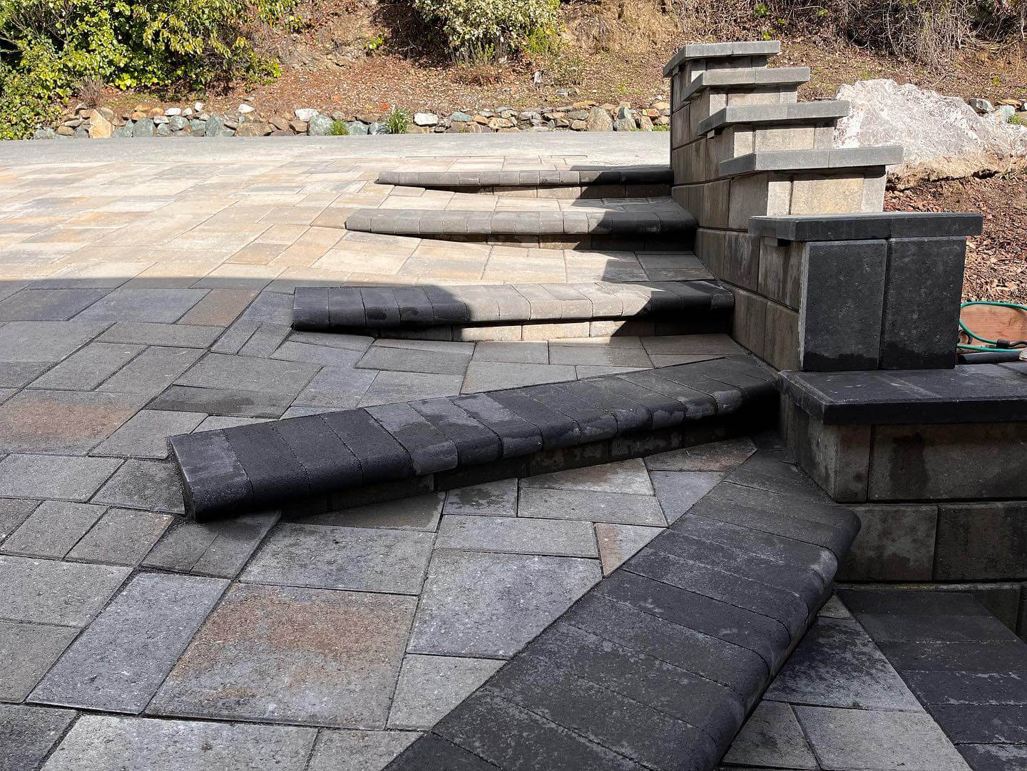 Multi-level stone paver patio with curved steps and retaining wall columns