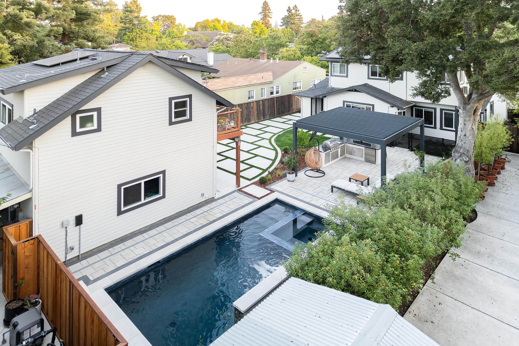 Backyard by Keystone Yards with a lap pool, pergola-covered outdoor kitchen, and geometric turf-and-paver pathway, part of the landscape service area in Napa, CA.