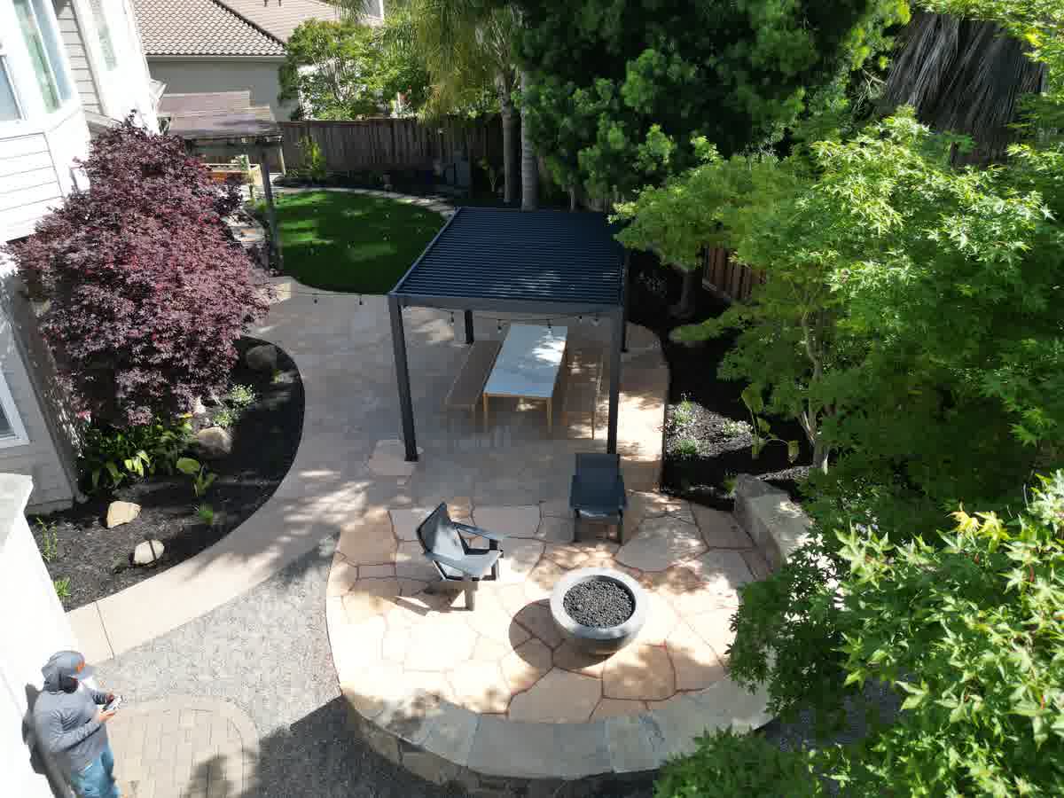 Custom backyard landscape design featuring a stone patio, fire pit, and modern pergola in Napa, CA.