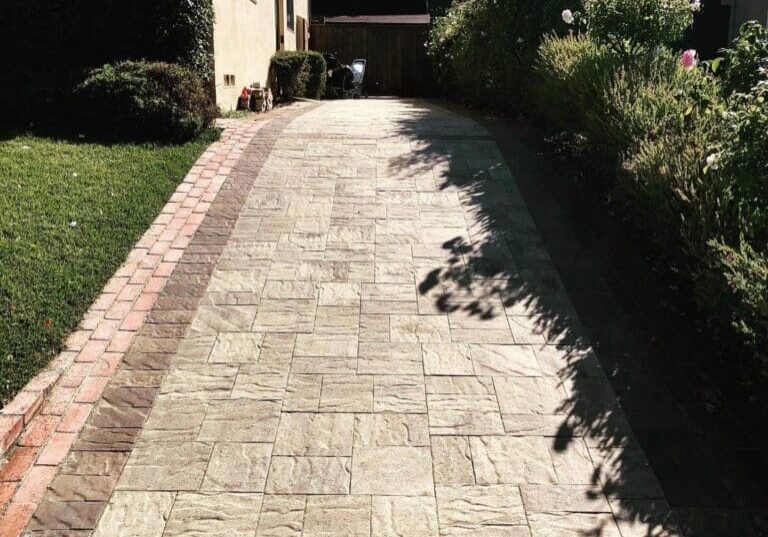 Stone paver side yard pathway bordered by green lawn and flowering shrubs