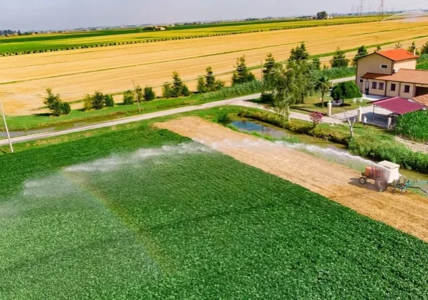Aerial view of a farm with irrigation sprinklers watering green crop fields