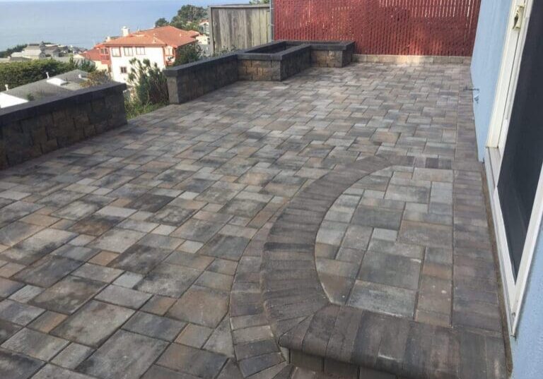 Stone paver patio with raised planter walls and ocean view in the background