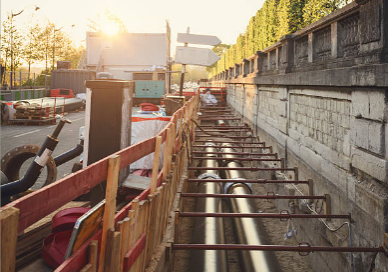 Underground pipeline installation in an open construction trench at sunset
