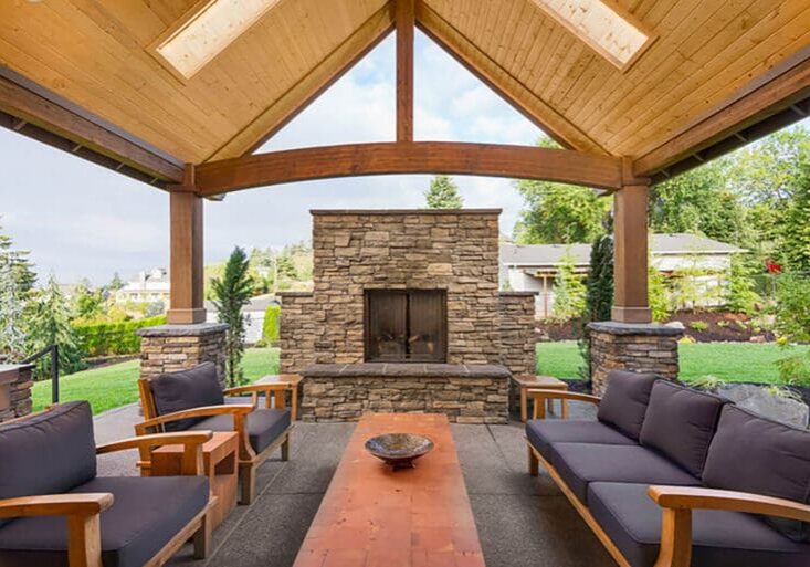 Custom stone outdoor fireplace under a wood-beam pavilion with luxury patio seating in Napa County