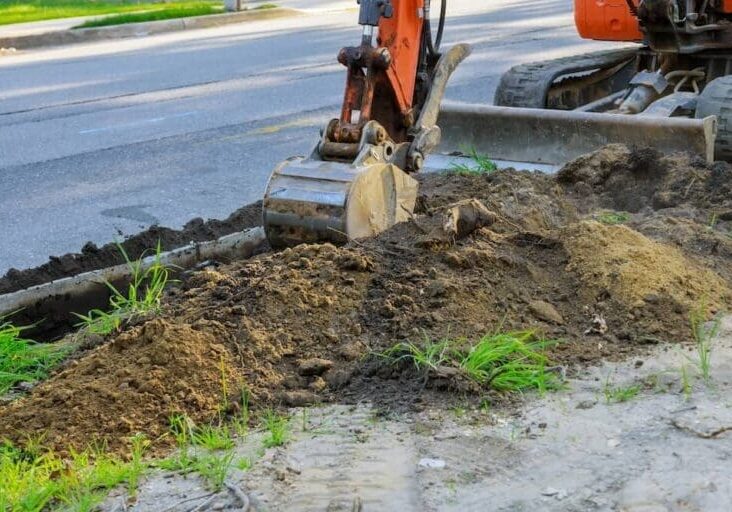 Excavator digging soil during outdoor landscaping and grading project
