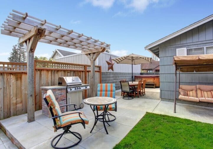 outdoor living spaceBackyard patio with wood pergola, built-in brick grill, colorful patio furniture, and porch swing