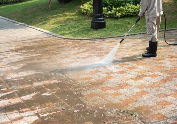 Worker pressure washing a brick paver pathway outdoors