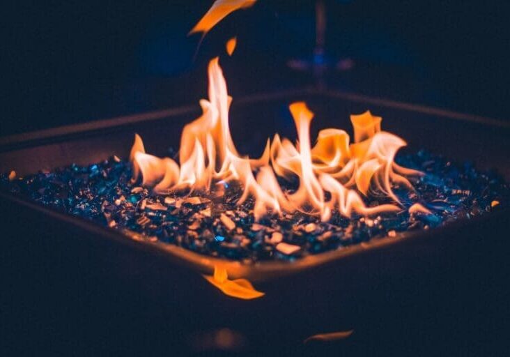 Close-up of outdoor gas fire pit with blue glass rocks at night