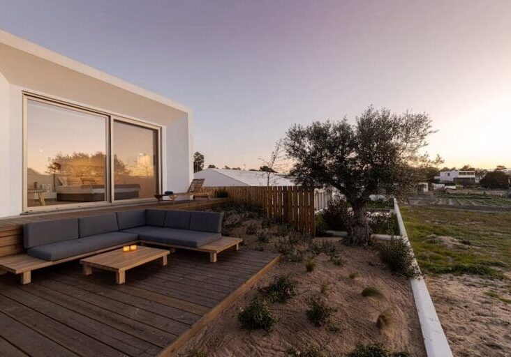 Modern outdoor deck with sectional sofa and sandy landscape at sunset