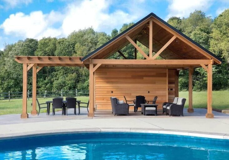 Wooden pool pavilion with outdoor seating and pergola beside a backyard swimming pool